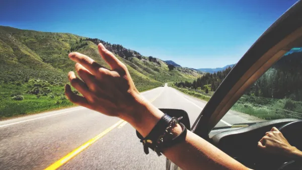 Mano saliendo por la ventanilla del coche en carretera, sensación de libertad y viaje